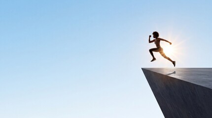 Fototapeta premium Silhouette of a motivated young woman jumping off a concrete ledge into the clear blue sky with large negative space on the left side, representing freedom, courage, and taking a leap of faith.