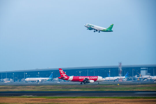 Tangerang, Indonesia - August 25, 2026: Citilink Airbus A320 taking off while AirAsia Airbus A320 taxis at Soekarno-Hatta International Airport.