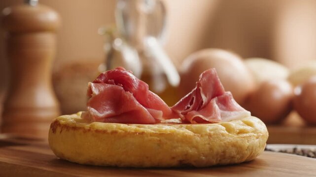 Spanish omelette with jamon serrano, tortilla and iberico cured ham appetizer on wooden table, traditional Spanish breakfast close up in cafe