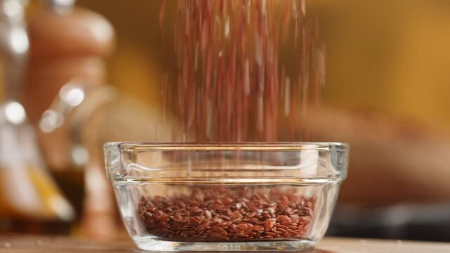 Flax seeds in wooden spoon and bowl macro close up, golden and brown linseed grains falling, raw flaxseed healthy omega 3 superfood ingredient texture
