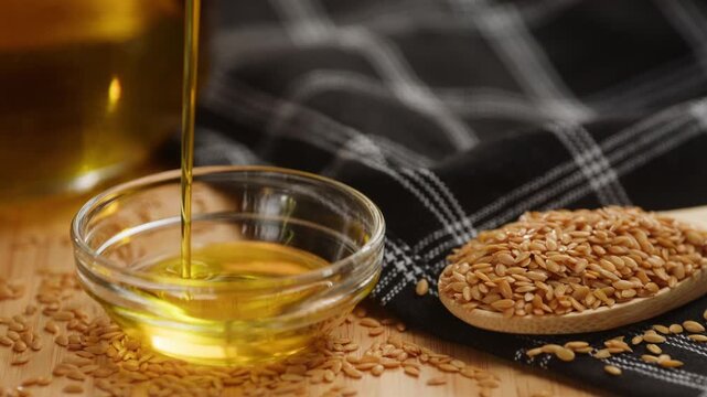 Flax oil pouring into glass bowl on flax seeds, golden flaxseed and linseed oil with omega 3, like sunflower, sesame or extra virgin olive oil, macro close up