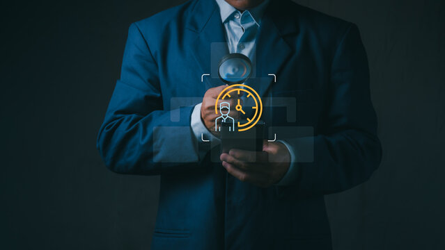 Businessman holds smartphone and a magnifying glass over virtual employee clock for human resources time tracking, workforce productivity, and attendance management.