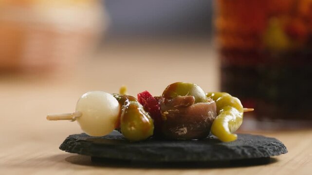 Gilda pintxo, traditional Spanish tapas with hot green pepper, anchovy, olives and pickled vegetables, served with vermouth