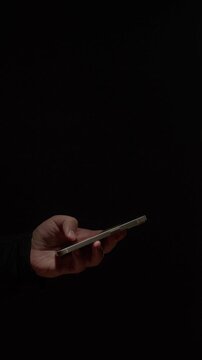 Phone at night, Close-up macro hands of a man scroll news feed on mobile phone app application. Screen of the mobile phone illuminates male hand. 