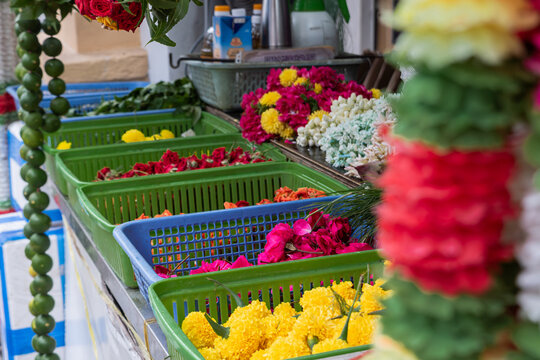 Row of colorful floral offerings and garlands prepared for Hindu temple rituals during Diwali season