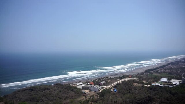 A panoramic view of Java's southern coast and the crashing waves of Parangtritis Beach, captured from the top of the Obelix cliff.