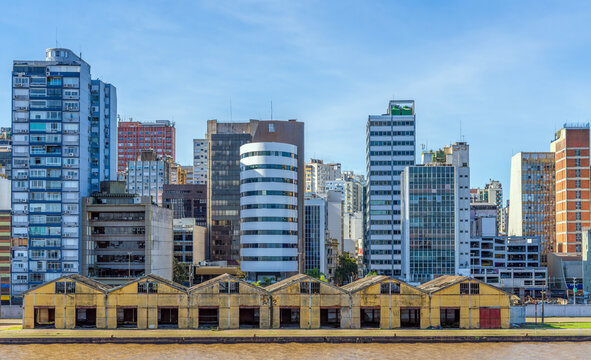 Panoramical view of the historic Cais Maua red docks along the Guaiba riverbank, with the urban skyline of Porto Alegre, Brazil, stretching beneath an expansive clear blue sky