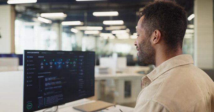 Developer programmer man coding software with confidence. He focuses on a computer screen in office, reviewing code and tracking results. Clear concept of coding success and achievement.