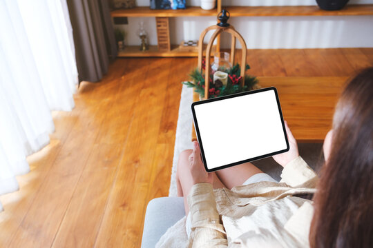 Top view mockup image of a woman holding tablet with blank desktop white screen at home