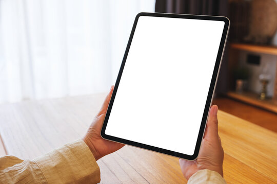 Mockup image of a woman holding tablet with blank desktop white screen at home