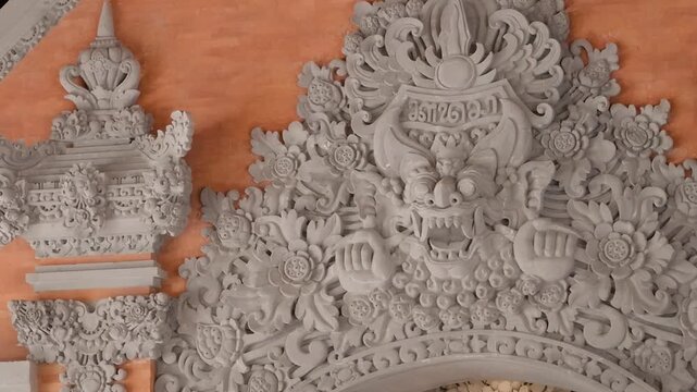 Close up of traditional Balinese floral stone carving with a mythical demon face mask