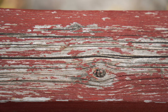 Close-up of weathered red painted wooden plank with peeling paint