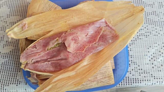 Unwrapping a fresh homemade tamale from a corn husk