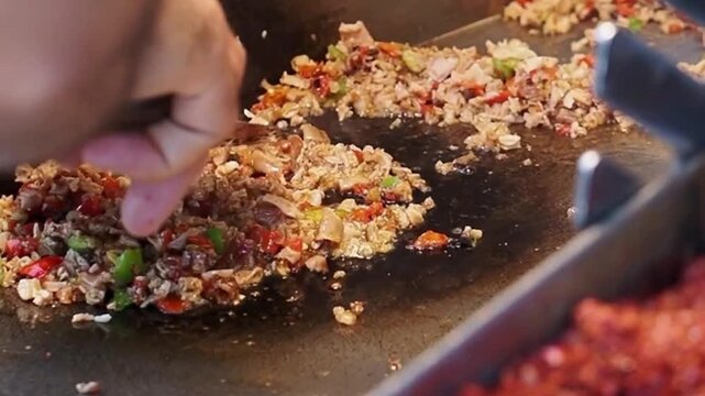 Chef hands cooking minced meat and vegetables on a flat griddle