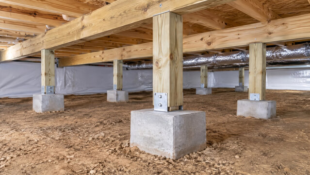 Interior Of A Residential Crawl Space With Concrete Footings And Wooden Floor Support, Underneath A Modern Home Construction
