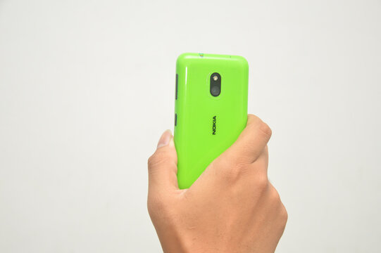 Central Java, Indonesia - October 4, 2026: Hand holding bright green Nokia smartphone isolated on white background.