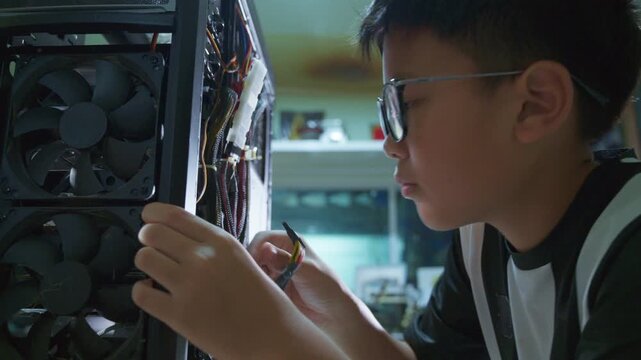 Young boy concentrating while repairing and assembling hardware inside an open desktop computer case at home, learning technology and problem solving skills