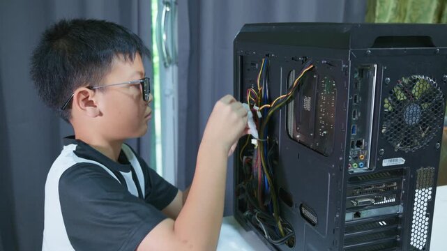 Young boy concentrating while repairing and assembling hardware inside an open desktop computer case at home, learning technology and problem solving skills