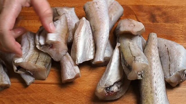 Pieces of sliced raw fresh Pollock fish on a wooden cutting board. Close up