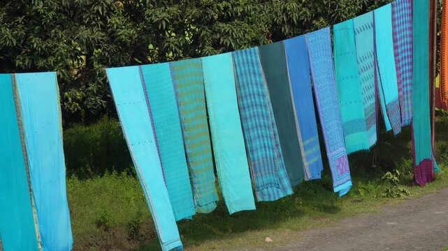 Colorful woven fabrics hanging on a clothesline in sunlight