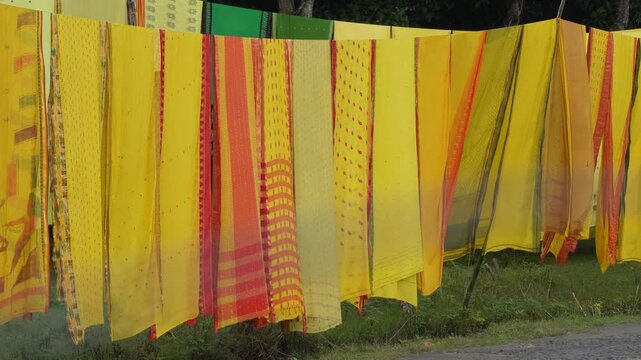 Bright yellow and orange sarees drying in sunlight