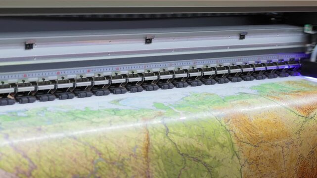Large format printer in motion creating big map image on paper for exhibition display or commercial use.