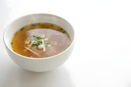Bowl of Traditional Hot Soup with Fresh Herbs on White Background
