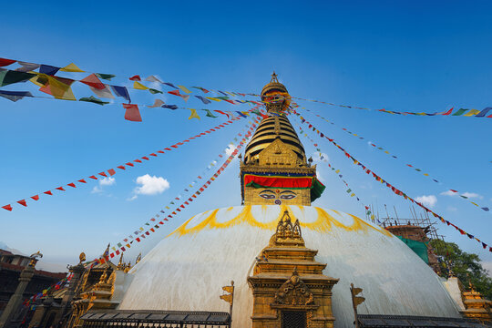 Boudhanath Stupa in Kathmandu, Nepal with colorful prayer flags under a clear blue sky