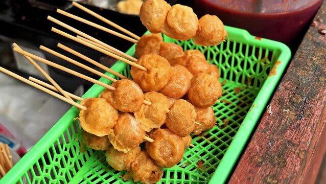 Delicious fried tapioca meatballs skewers in green basket, traditional local Indonesian street food snack cilor close up. 4K