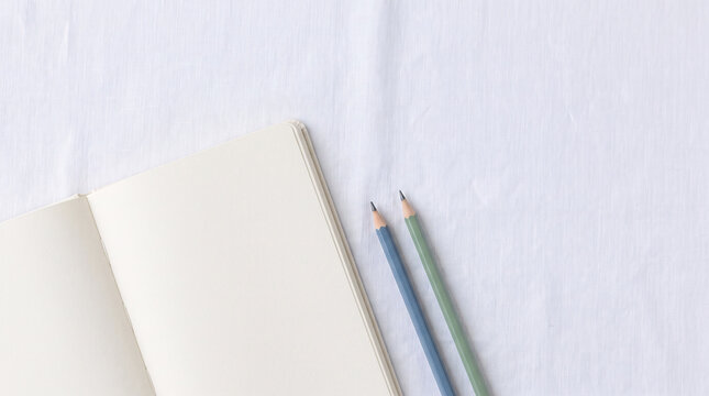 Carnet ouvert et crayons sur un tissu clair