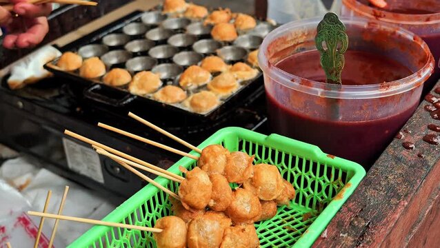 Deep fried tapioca starch balls on bamboo skewers served in a plastic basket. Popular Indonesian street food snack known as cilor or cilok. 4K