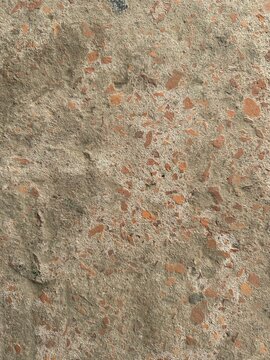 Textured concrete surface with embedded reddish-brown aggregate stones