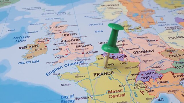 Green pushpin marking location on Europe map, France and Belgium highlighted, travel destination concept.