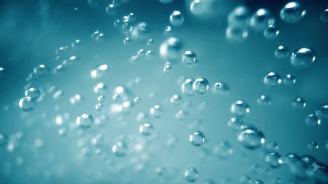 Abstract underwater scene with countless small, clear, and shimmering air bubbles ascending slowly in a cool blue liquid creating a relaxing background motion.