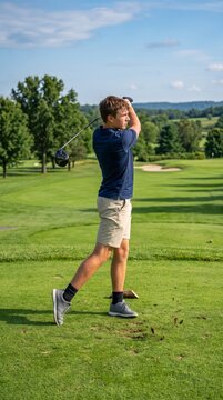 Young man swinging a golf club on a sunny golf course  