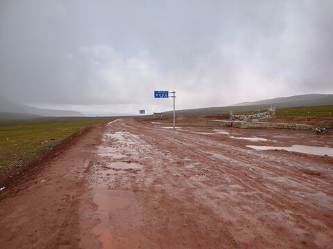 Muddy road in an open area under overcast sky