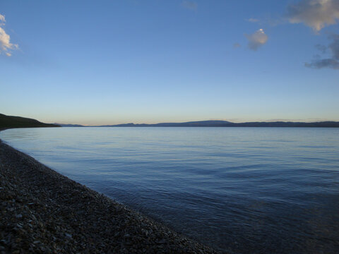 Calm water surface with clear blue sky and shoreline in view