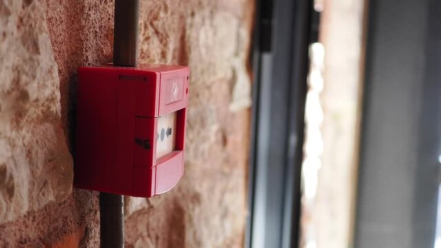 A bright red fire alarm box mounted on the wall of a building