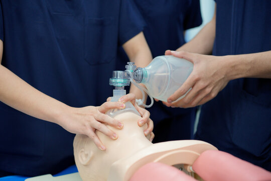 Healthcare professionals practicing proper C-clamp technique for bag-valve-mask ventilation during resuscitation training. 