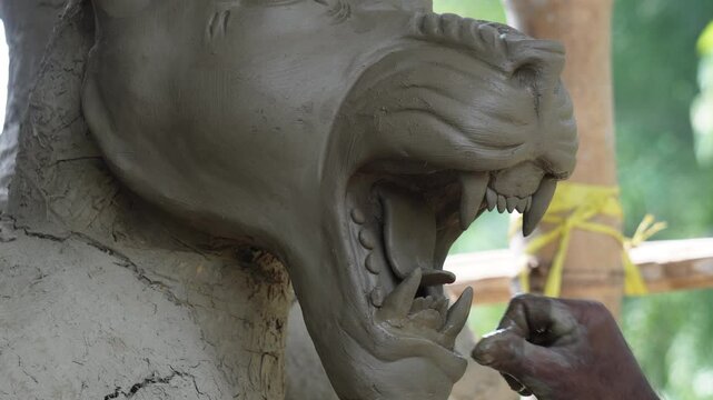 Artisan sculpting a clay lion head for durga puja in kumortuli