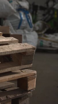 Rough Timber Storage. Wooden Pallets In Industrial Setting. Dim Warehouse With Stacked Wooden Shipping Pallets. Media