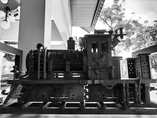 Side view of a detailed wooden model of an old-fashioned steam locomotive train. Black. White. © Putradigitalid