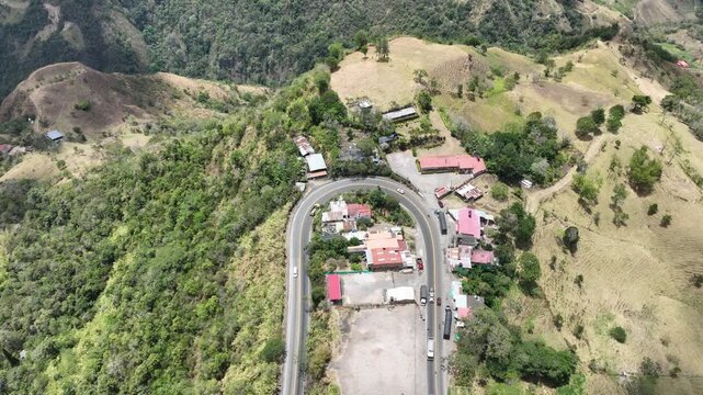Heavy Truck Traffic on Winding Mountain Highway at Alto de La Mona in Guaduas, Colombia. Establishing Shot. Aerial View.