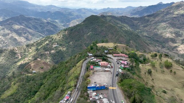 Heavy Truck Traffic on Winding Mountain Highway at Alto de La Mona in Guaduas, Colombia. Establishing Shot. Aerial View.