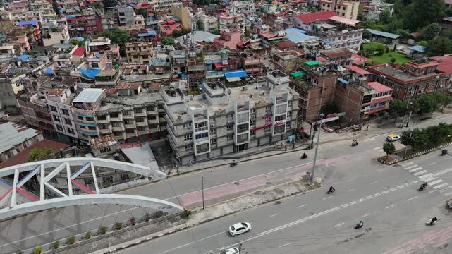 rone view of arched pedestrian bridge and multistory buildings in Kathmandu.