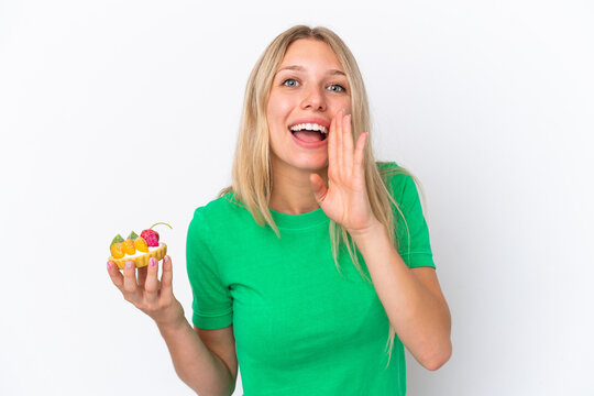 Young caucasian woman holding a tartlet isolated on white background shouting with mouth wide open