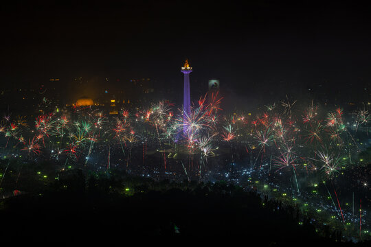 Rare and spectacular New Year's Eve fireworks illuminating the night sky over the National Monument (Monas) during a massive crowd celebration in Jakarta, Indonesia