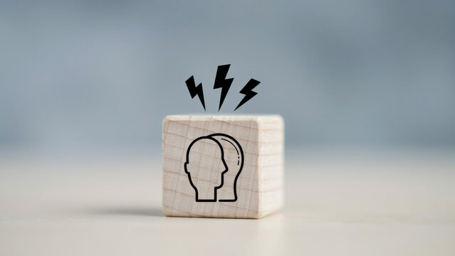 Wooden block with a human head icon and lightning bolts on a light wooden surface with representing stress mental wooden cube with heads three lightning, cube