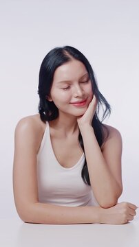 A beautiful Asian woman with clean glowing skin smiles at the camera. Perfect for skincare, beauty product, and cosmetic advertisements.