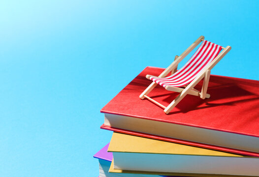 Summer Holiday Reading Concept with Deck Chair and Books in Sunlight